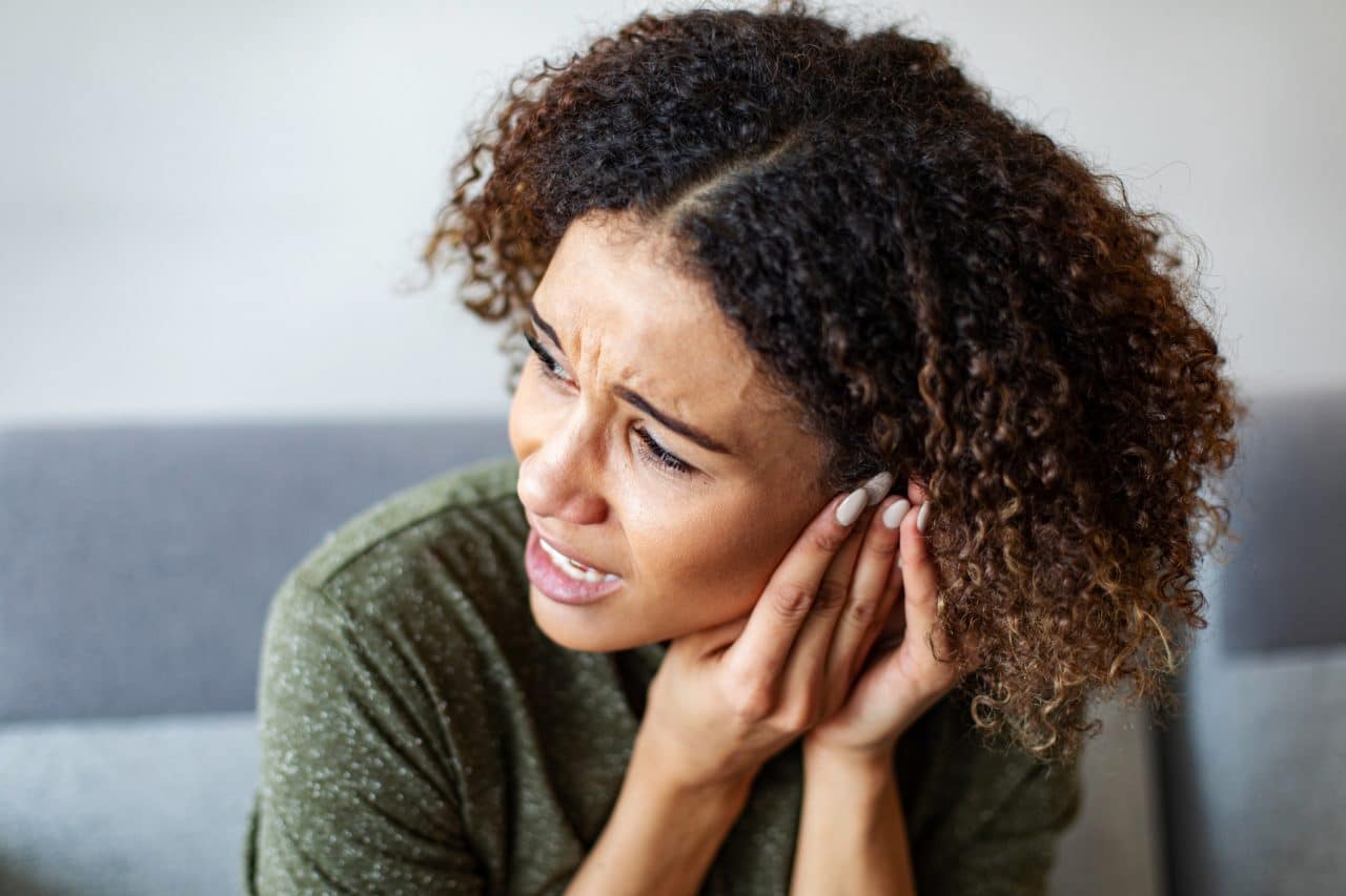 Woman with tinnitus putting her hand to her ear.