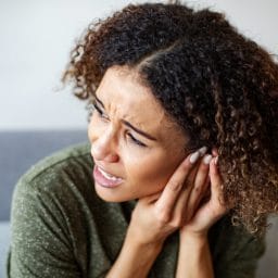 Woman with tinnitus putting her hand to her ear.