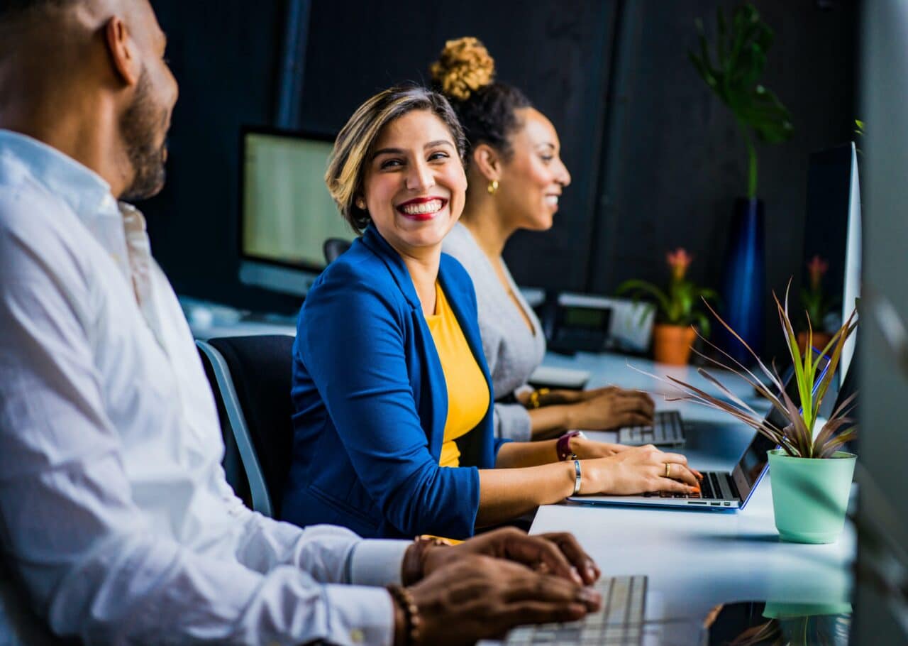 Woman at a new job smiling and talking with her coworkers.