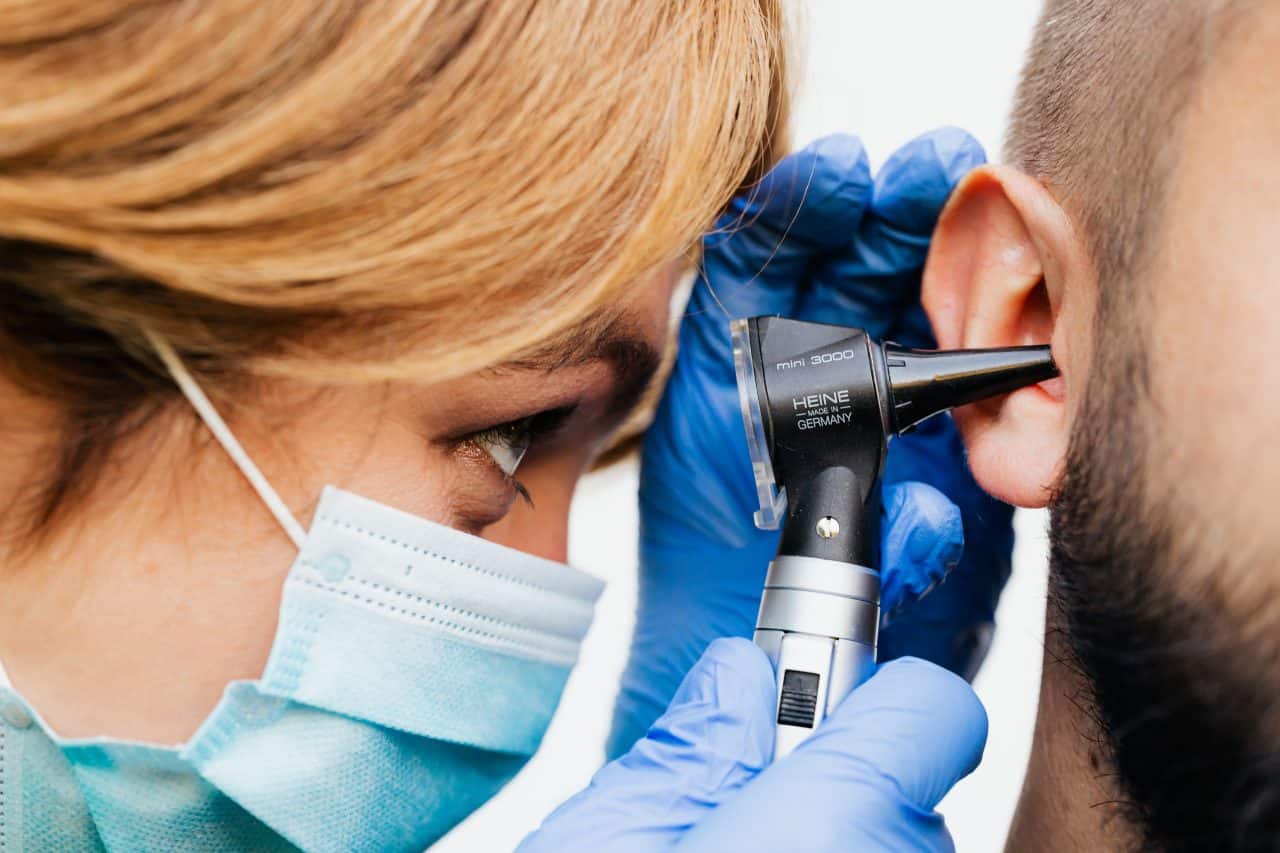 Audiologist examining a man's ear.