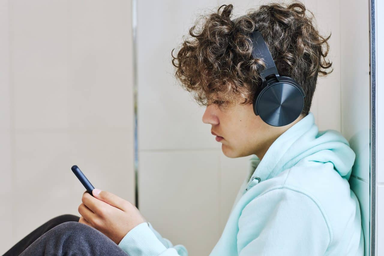 a child scrolls his phone with headphones on