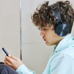 a child scrolls his phone with headphones on