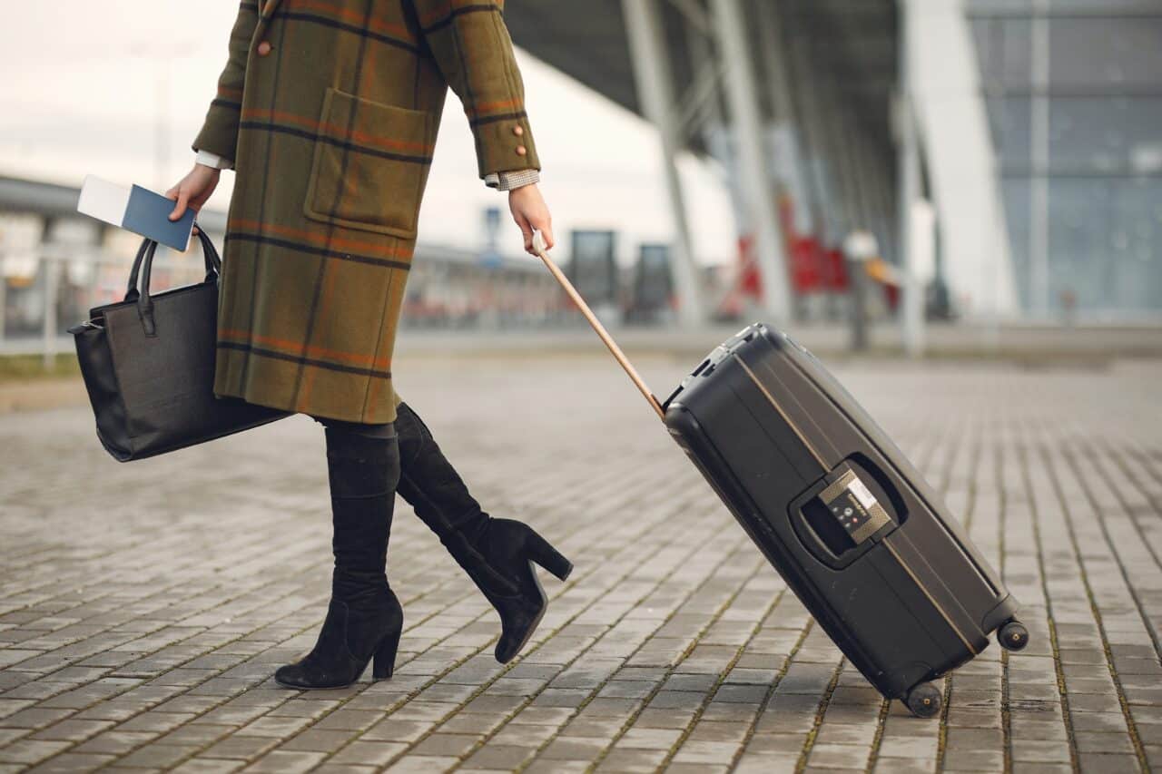 Woman headed to an airport with her suitcase.