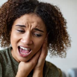 Woman with tinnitus holding her ear looking upset