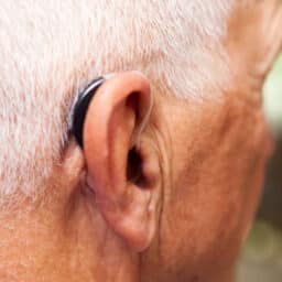 Senior man wears a hearing aid