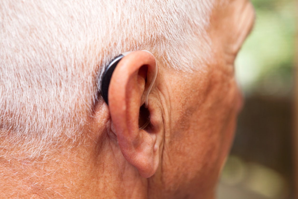 Senior man wears a hearing aid