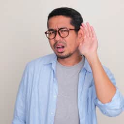 Man with his hand to his ear trying to understand