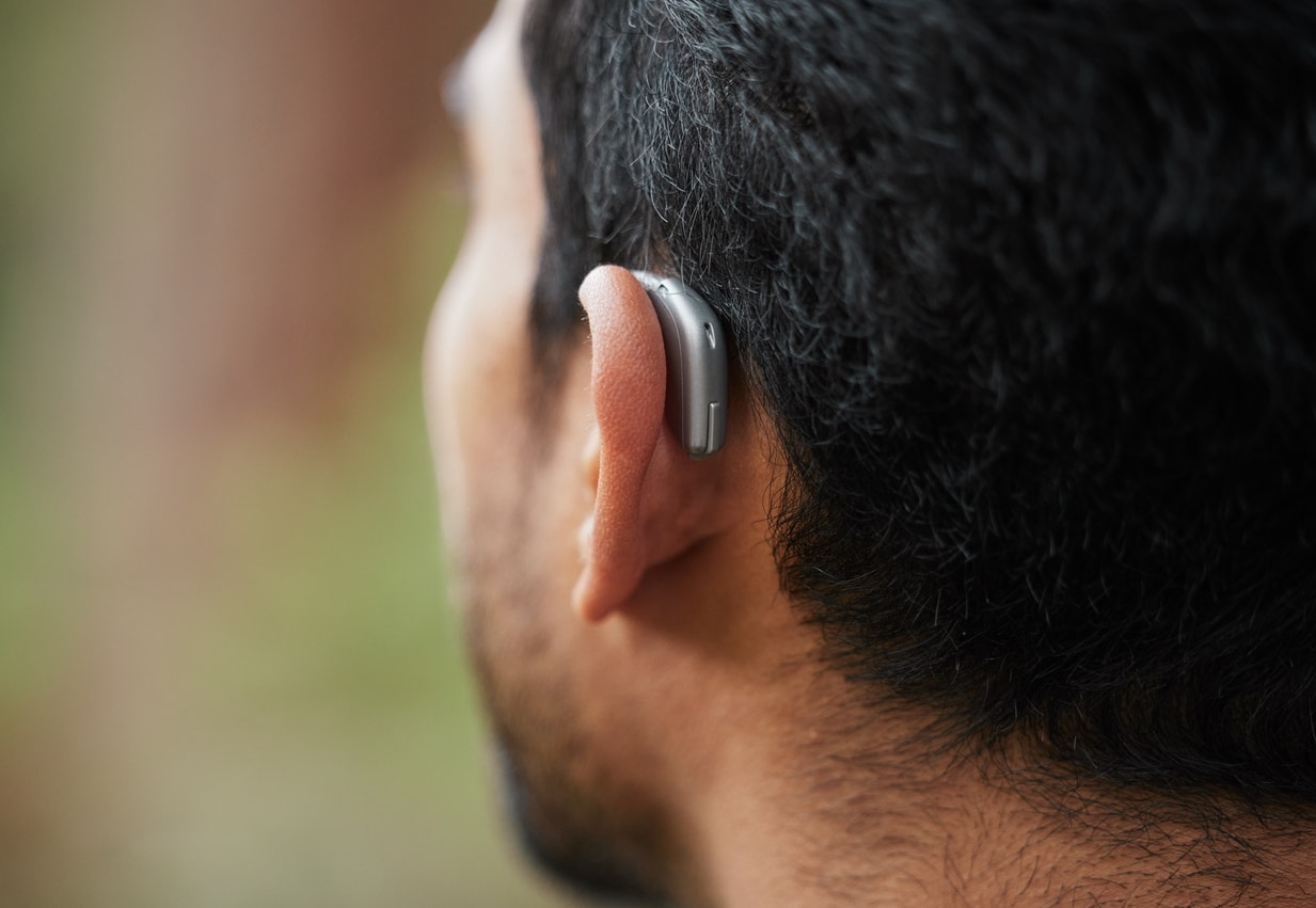 Close up photo of a man wearing a behind-the-ear hearing aid.