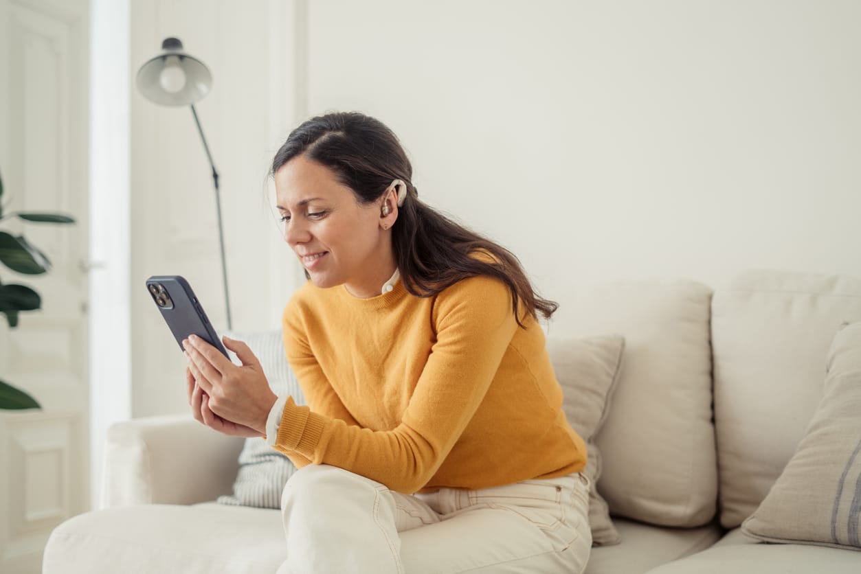 Woman with a hearing aid looking at her phone.